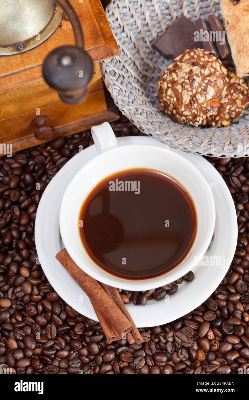 Vue supérieure de la tasse de café et de café torréfié avec moulin manuel en bois rétro, biscuits, barres de chocolat, cannelle Banque D'Images