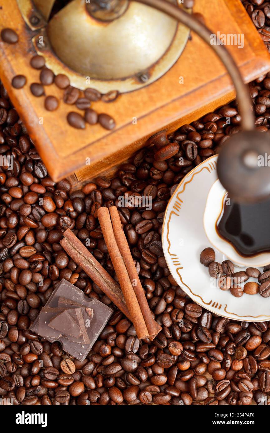 Au-dessus de la petite tasse de café et de café torréfié avec moulin manuel en bois rétro, la cannelle, les barres de chocolat close up Banque D'Images