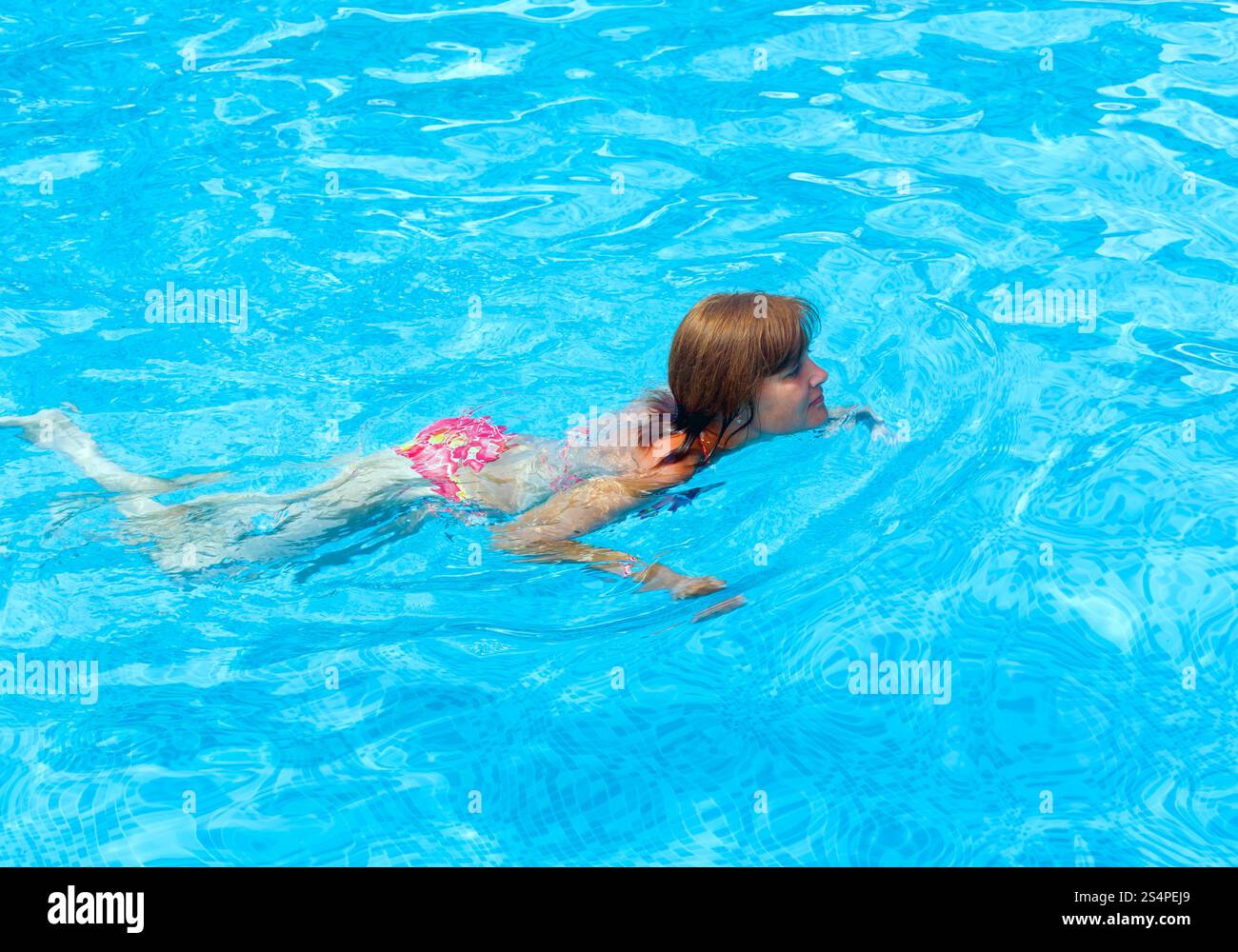 Femme à nager dans la piscine extérieure ouverte en été. Banque D'Images