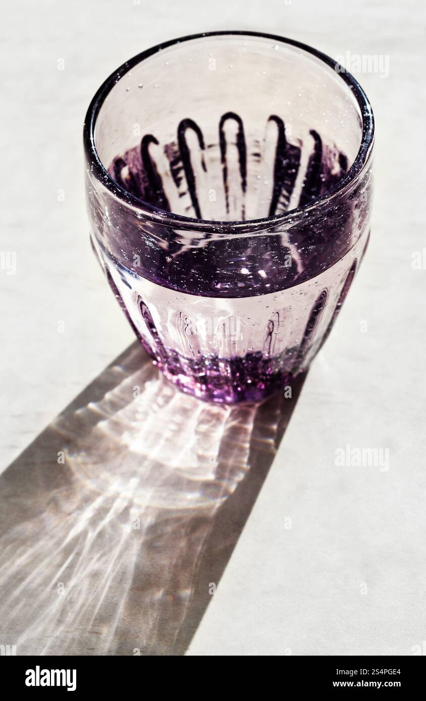 Verre à facettes avec l'eau potable éclairées par la lumière du soleil Banque D'Images