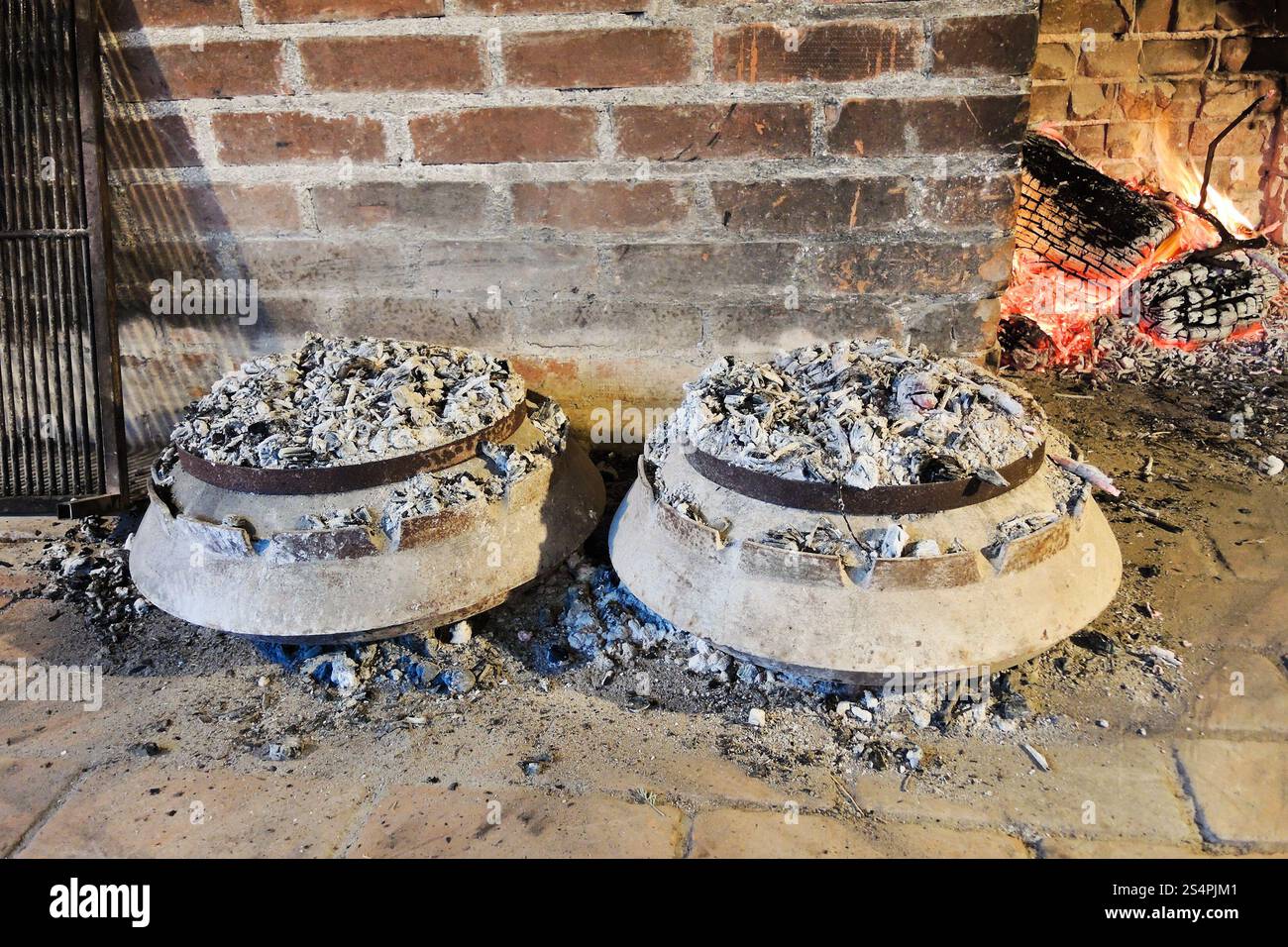 Cuisson du péka traditionnel dalmate dans des pots en métal sous des charbons brûlants Banque D'Images