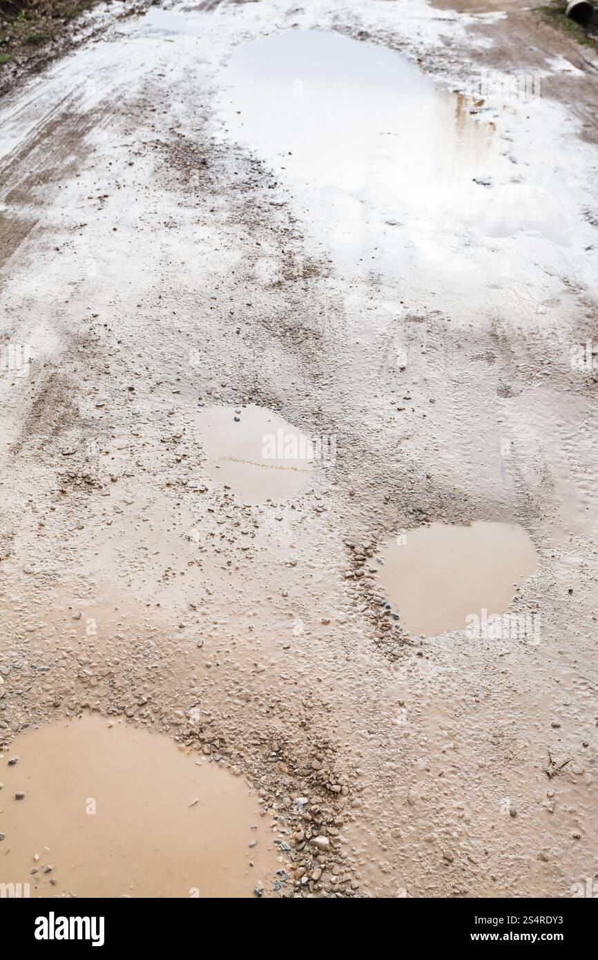 route terrestre avec des flaques pluvieuses dans le jour de printemps Banque D'Images