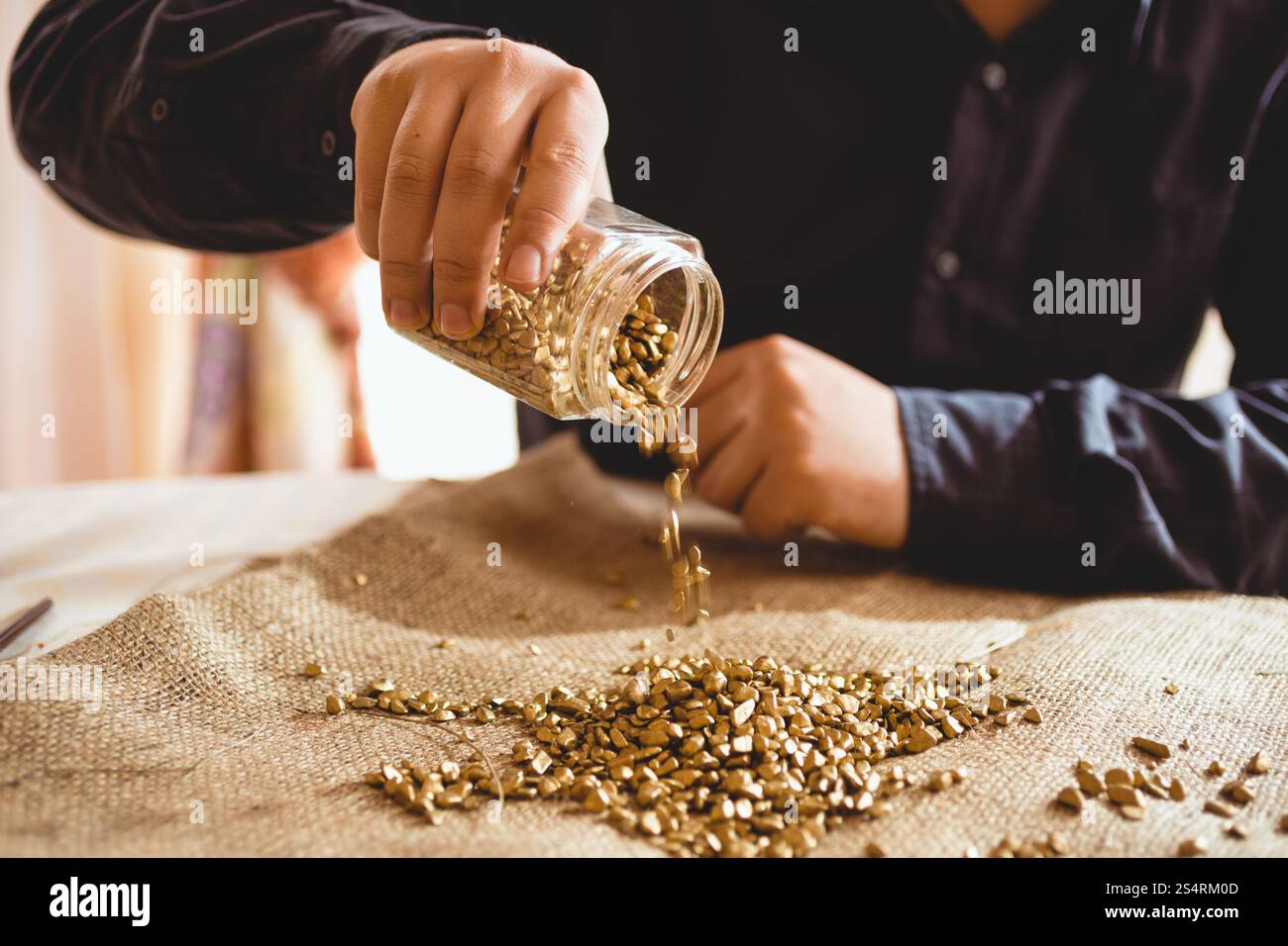 Mineur de jeunes hommes assis à table et verser de l'or glass jar Banque D'Images