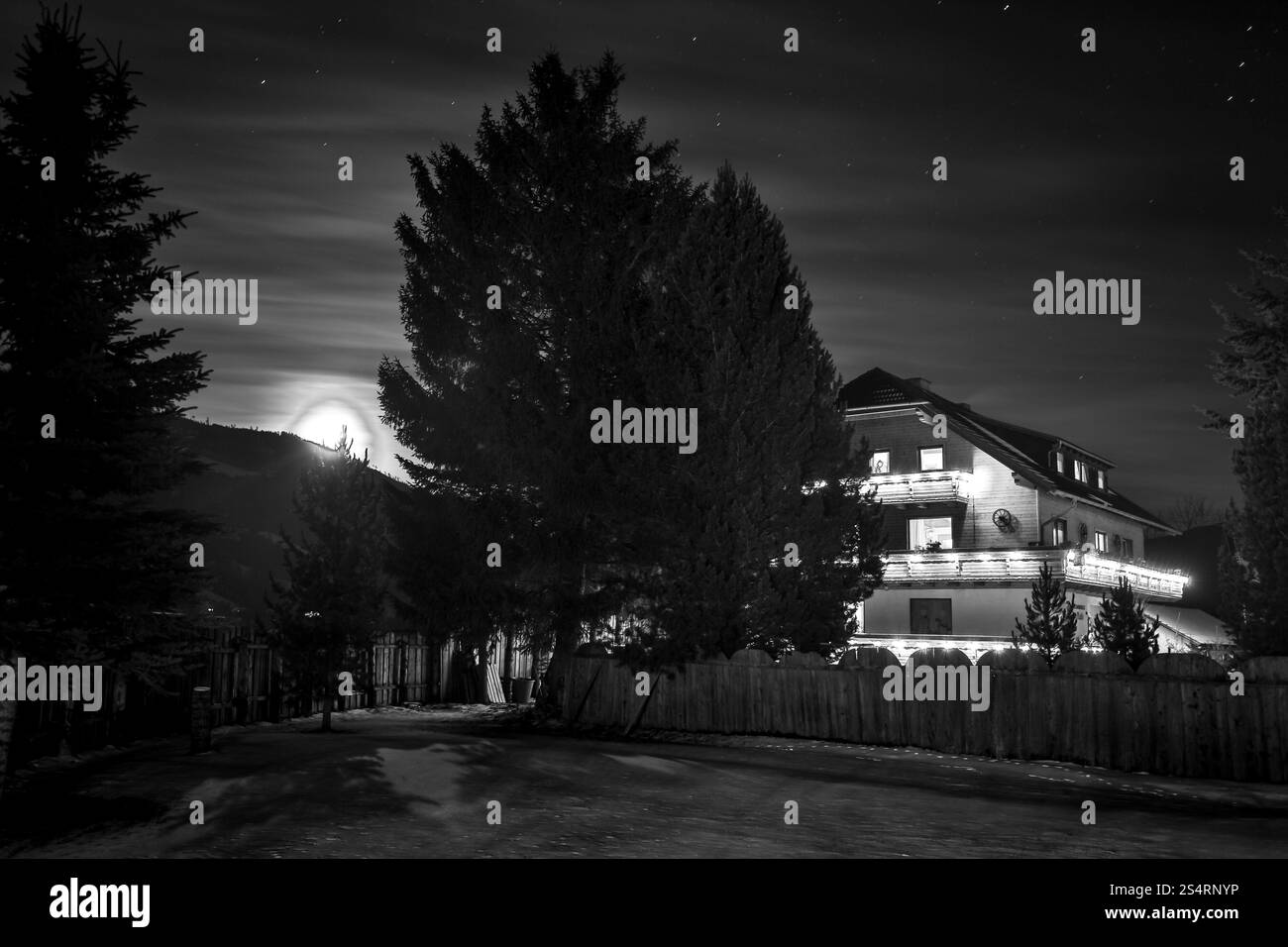 Photo en noir et blanc de chalet en bois dans le bois à la nuit étoilée Banque D'Images