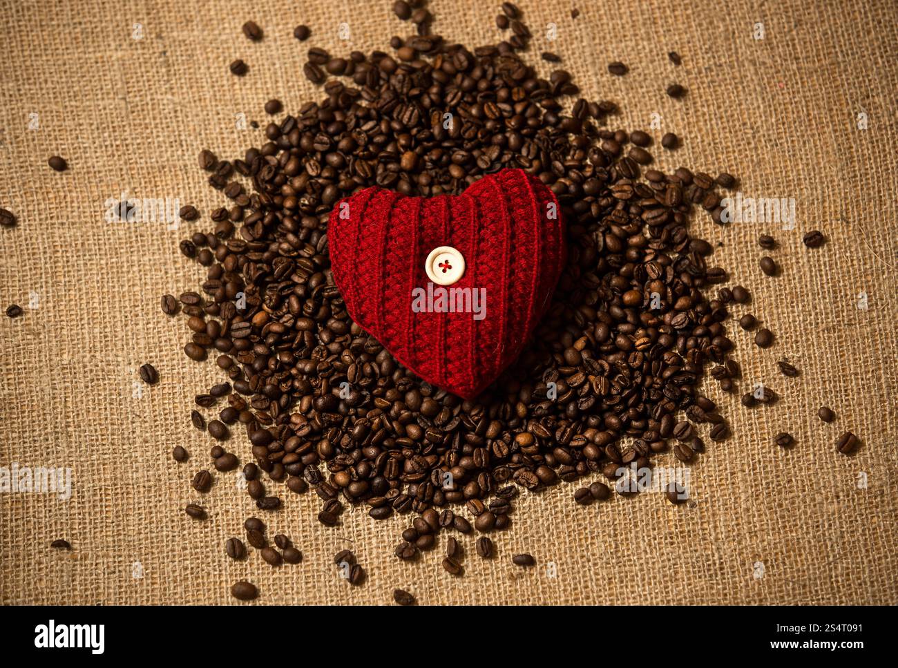 Libre de photo conceptuelle coeur rouge couché sur tas de grains de café Banque D'Images