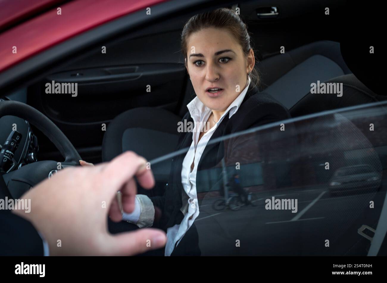 Le cambrioleur menace une jeune femme d'affaires assise en voiture Banque D'Images
