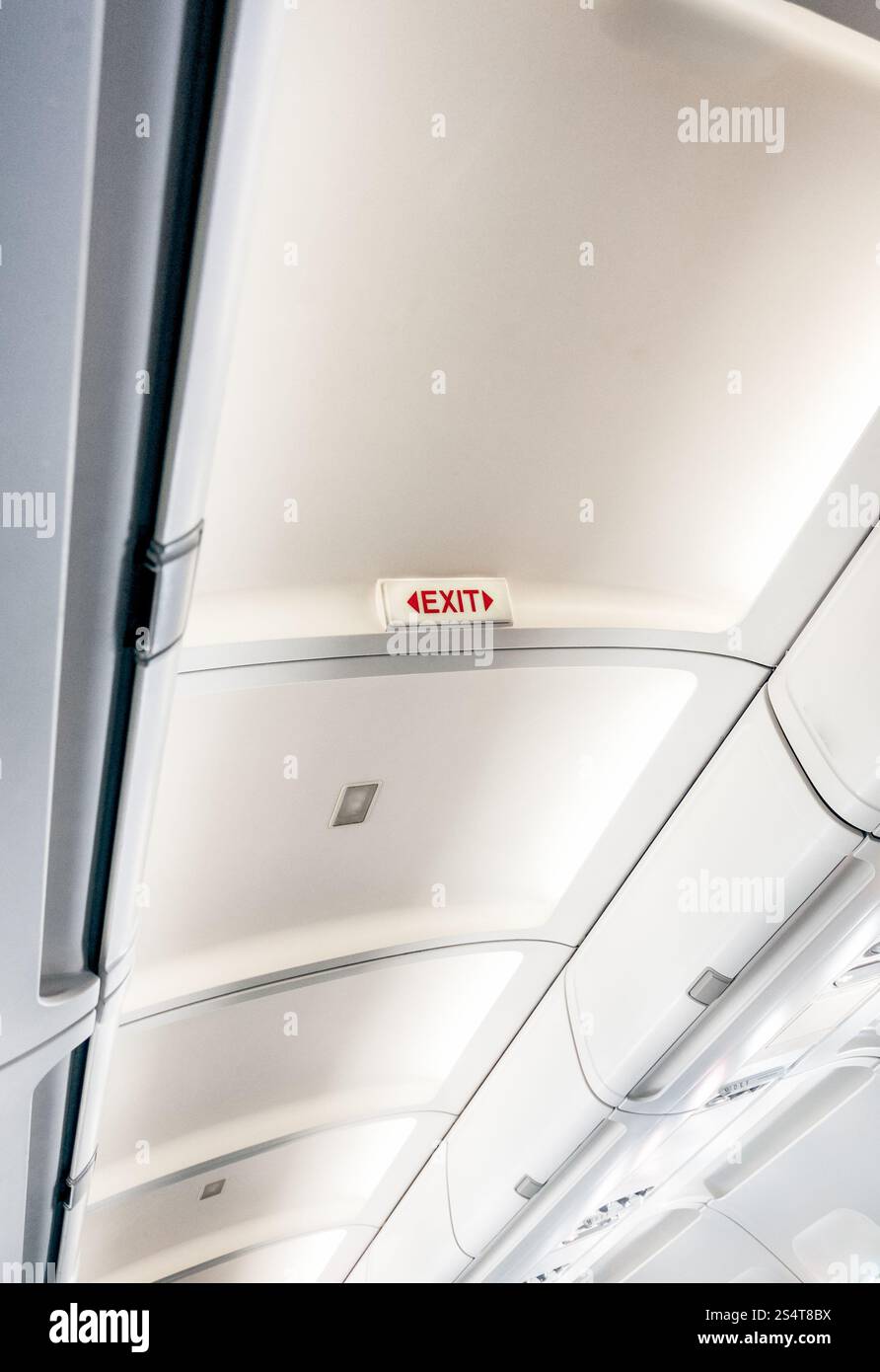 Photo de panneau de sortie sur un avion avec des lumières au plafond Banque D'Images