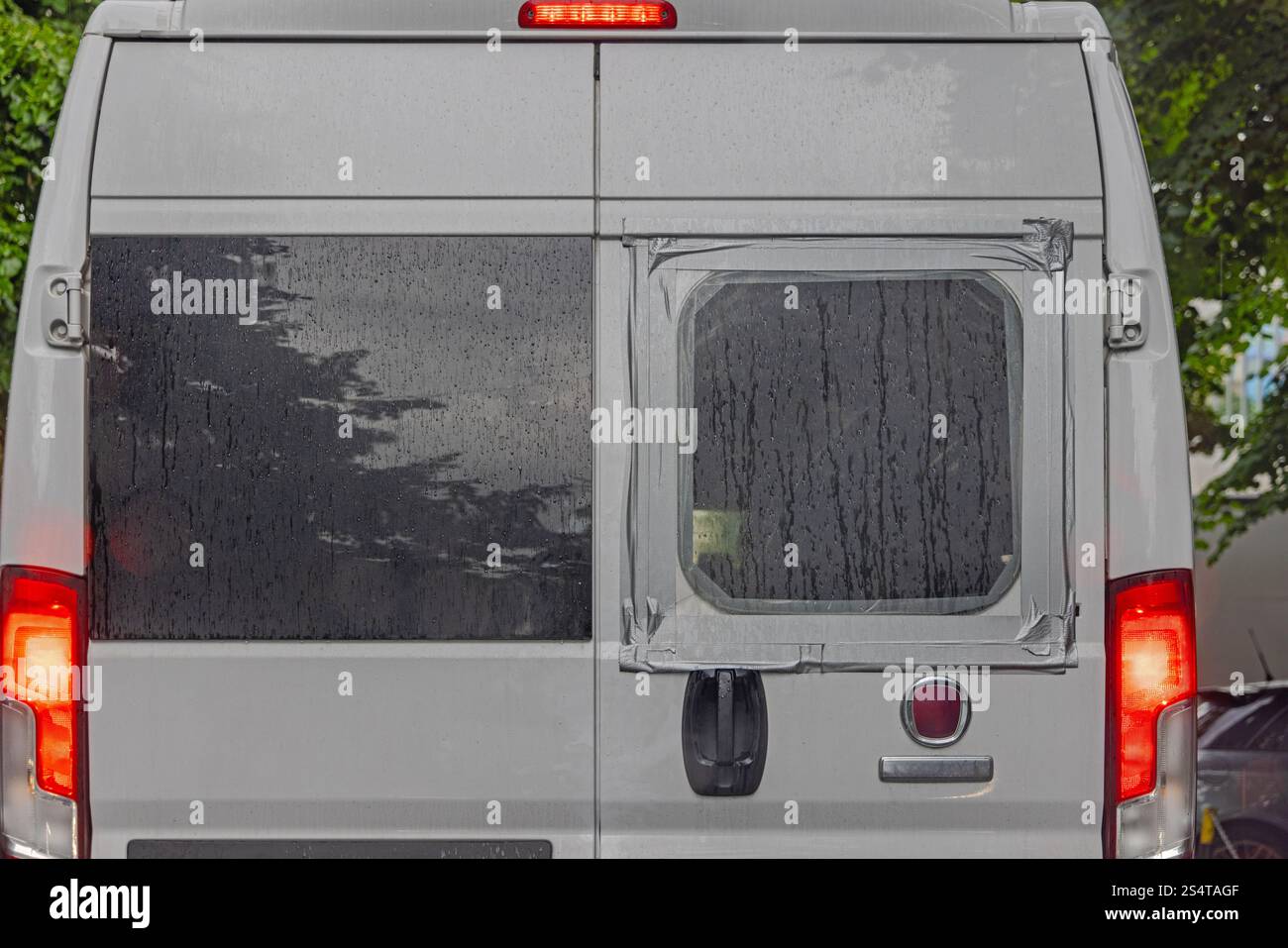 Lunette arrière brisée recouverte de plastique et de ruban adhésif chez Campervan Banque D'Images