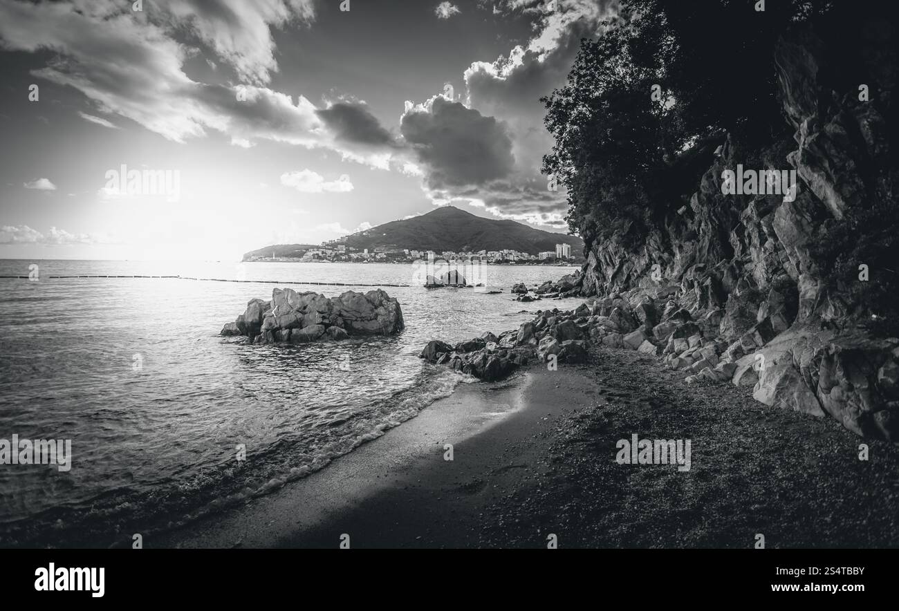 Le noir et blanc paysage de falaises avec des arbres debout en mer au coucher du soleil Banque D'Images