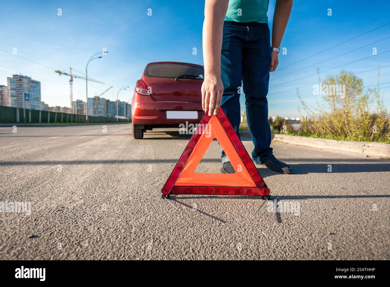 Jeune homme plaçant triangle rouge chanter sur route après accident de voiture Banque D'Images