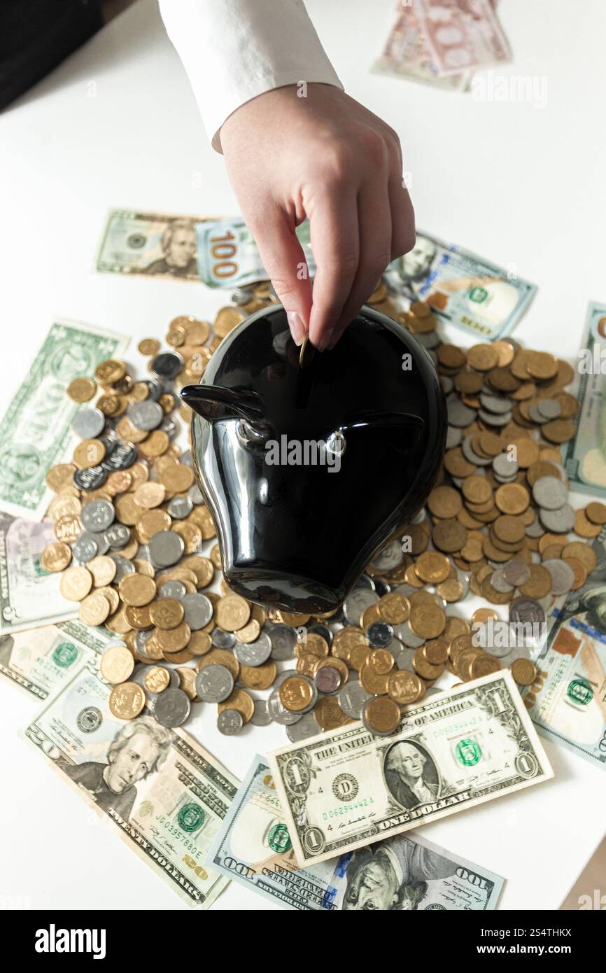 Photo conceptuelle de woman inserting coin in piggy bank Banque D'Images