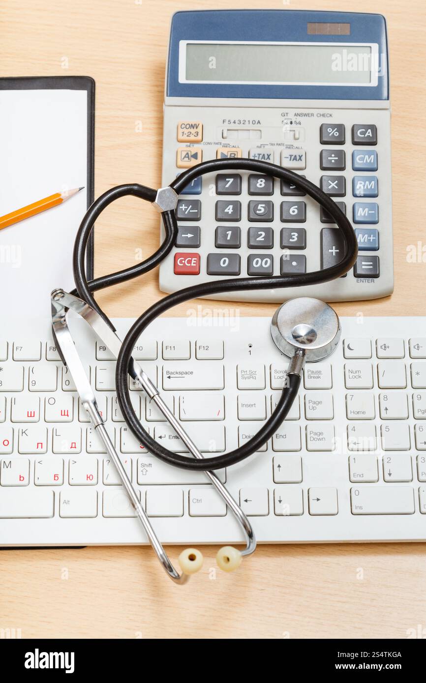 Medical still life - phonendoscope sur clavier blanc, calculatrice et presse-papiers vierges Banque D'Images
