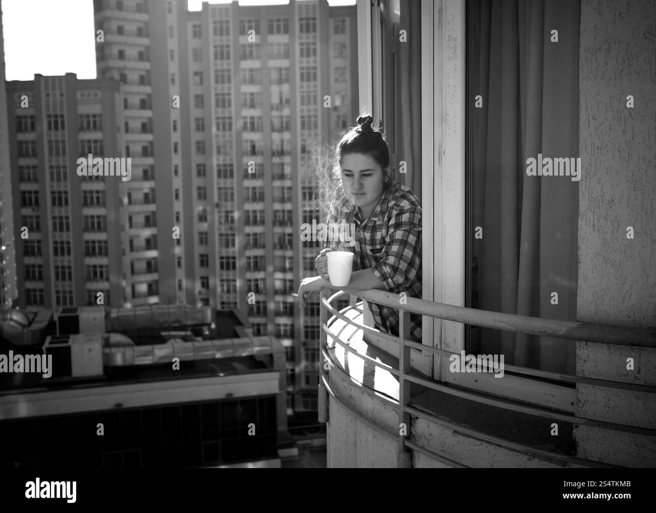 Photo en noir et blanc de femme déprimée de boire du café et fumer cigarette sur balcon Banque D'Images
