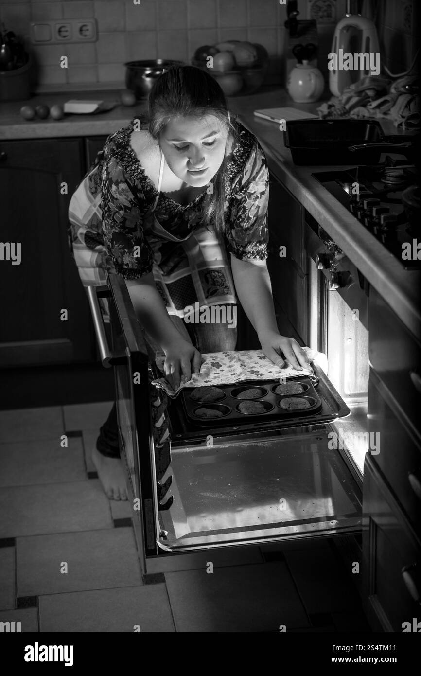 Le noir et blanc portrait of woman putting pan en four Banque D'Images