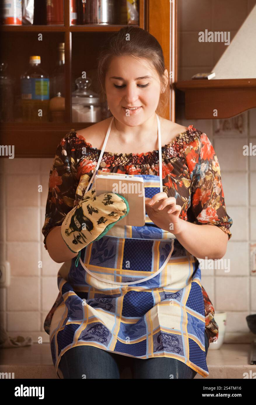 Closeup portrait de jeune femme au foyer à l'aide de tablet pendant la cuisson Banque D'Images