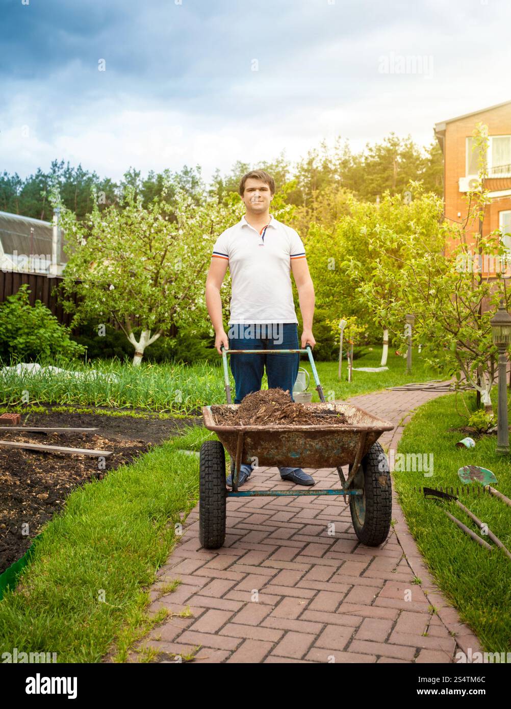 Bel homme transportant brouette à beau jardin Banque D'Images
