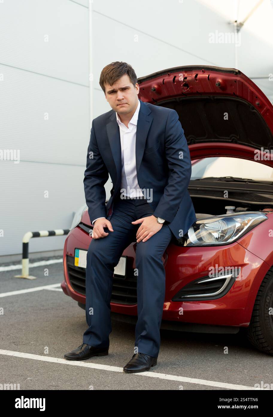 Young man sitting on casse voiture avec le capot ouvert Banque D'Images