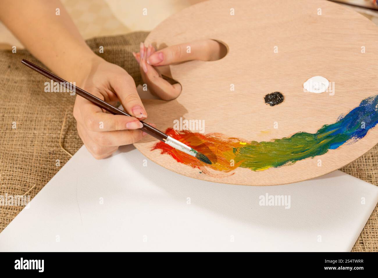 Macro photo de jeune femme peintre pinceau trempé dans la peinture sur palette Banque D'Images