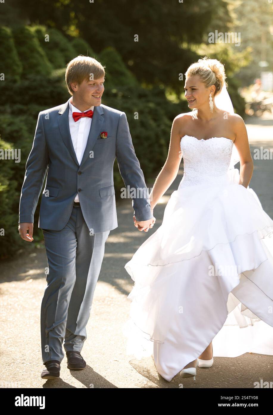 Belle mariée et marié tenant la main tout en marchant au parc Banque D'Images