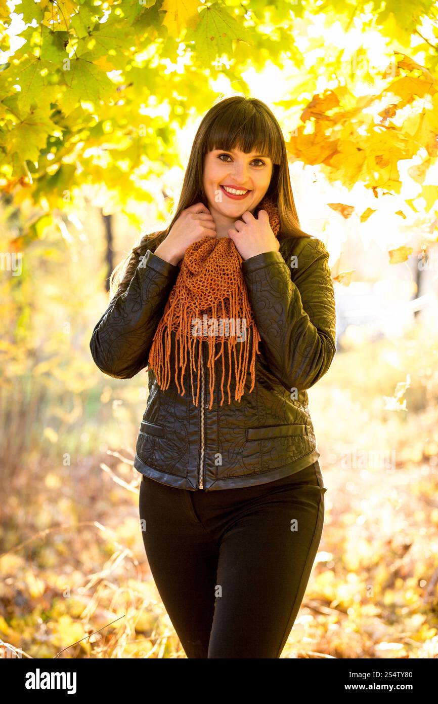 Portrait de femme brune souriante posant au parc d'automne à la journée ensoleillée Banque D'Images