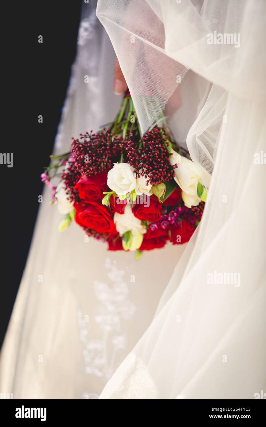 Gros plan photo de mariée tenant un bouquet de mariage de roses rouges et blanches Banque D'Images
