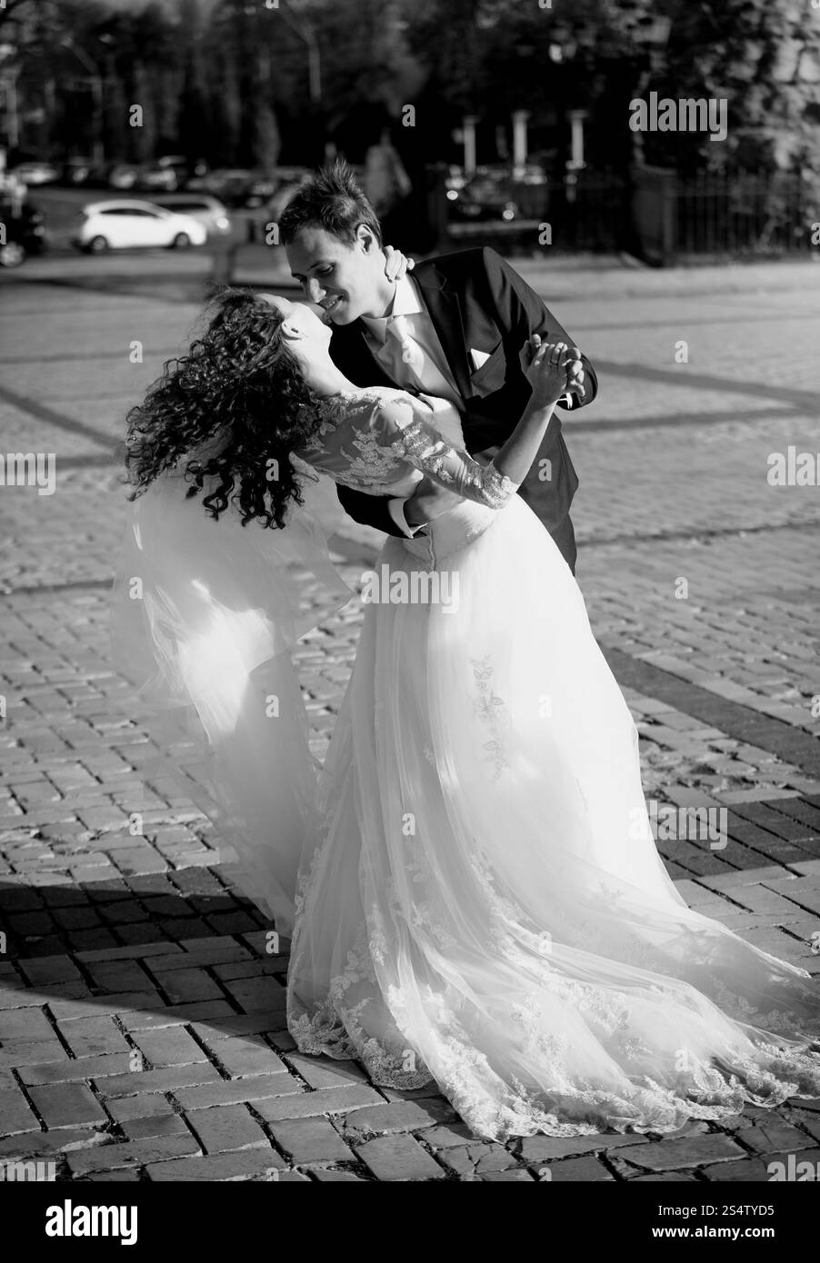Photo en noir et blanc de la mariée embrasser et le marié dans la rue à la journée venteuse Banque D'Images
