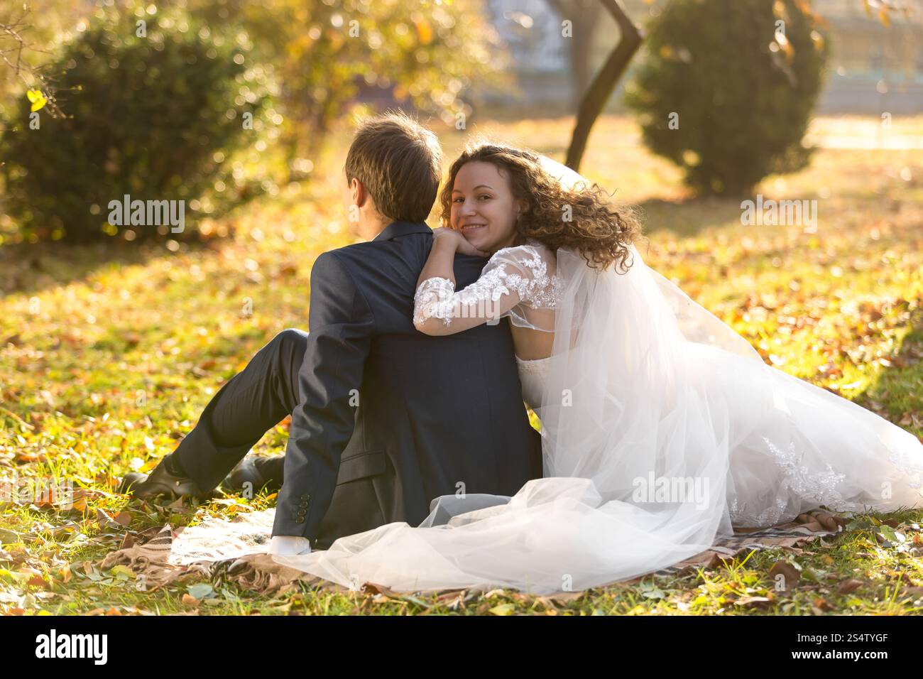 Beau couple juste marié se relaxant sur l'herbe au parc d'automne Banque D'Images
