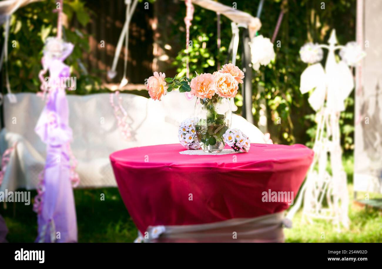 Gros plan de roses roses debout sur la table décorée à la cour Banque D'Images