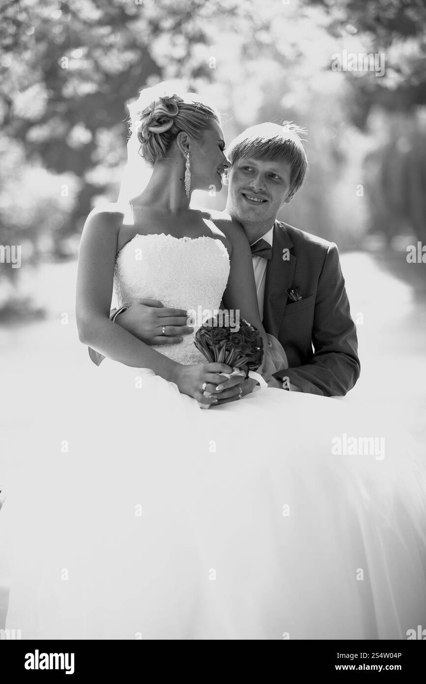 Portrait en gros plan noir et blanc de mariée heureuse et mariée s'embrassant sous le grand arbre Banque D'Images