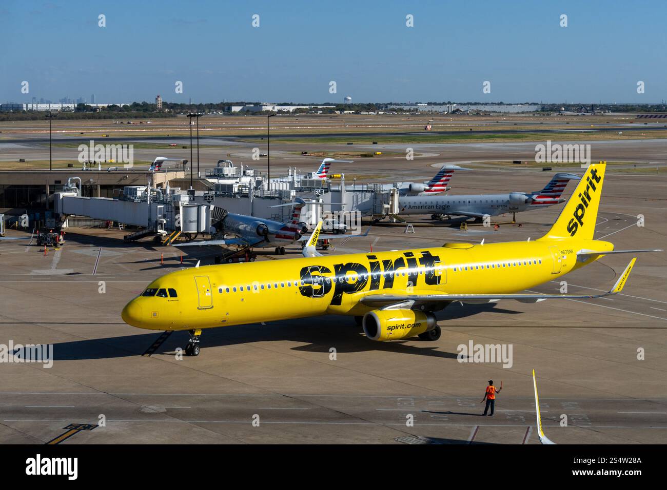 Un jet-taxi de Spirit Airlines vers sa porte d'embarquement à l'aéroport international de Dallas Fort Worth. Dallas, Texas. Un marshall de l'aéroport dirige le pil Banque D'Images
