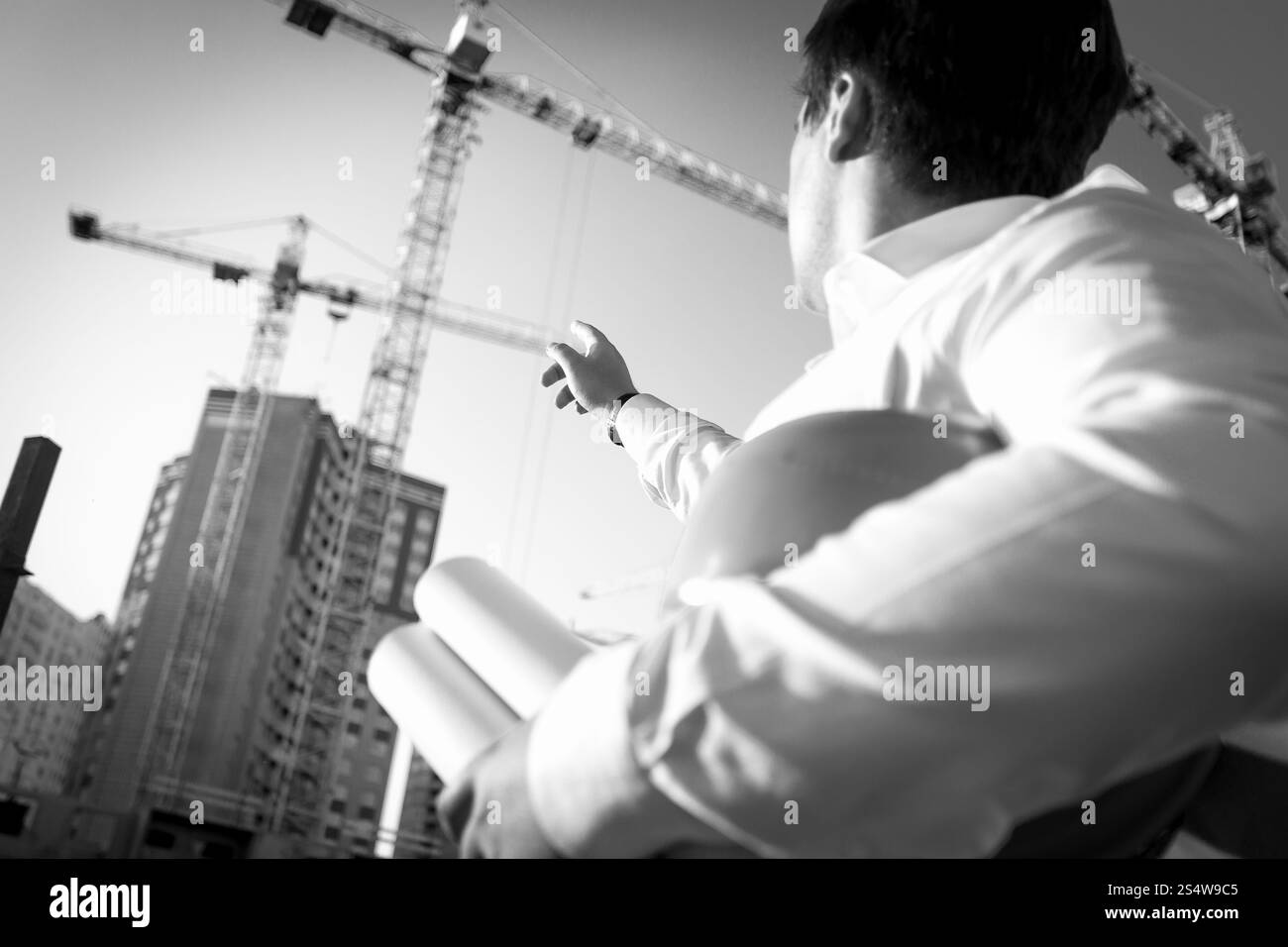 Noir et blanc photo gros plan de l'ingénieur en montrant le bâtiment en construction Banque D'Images