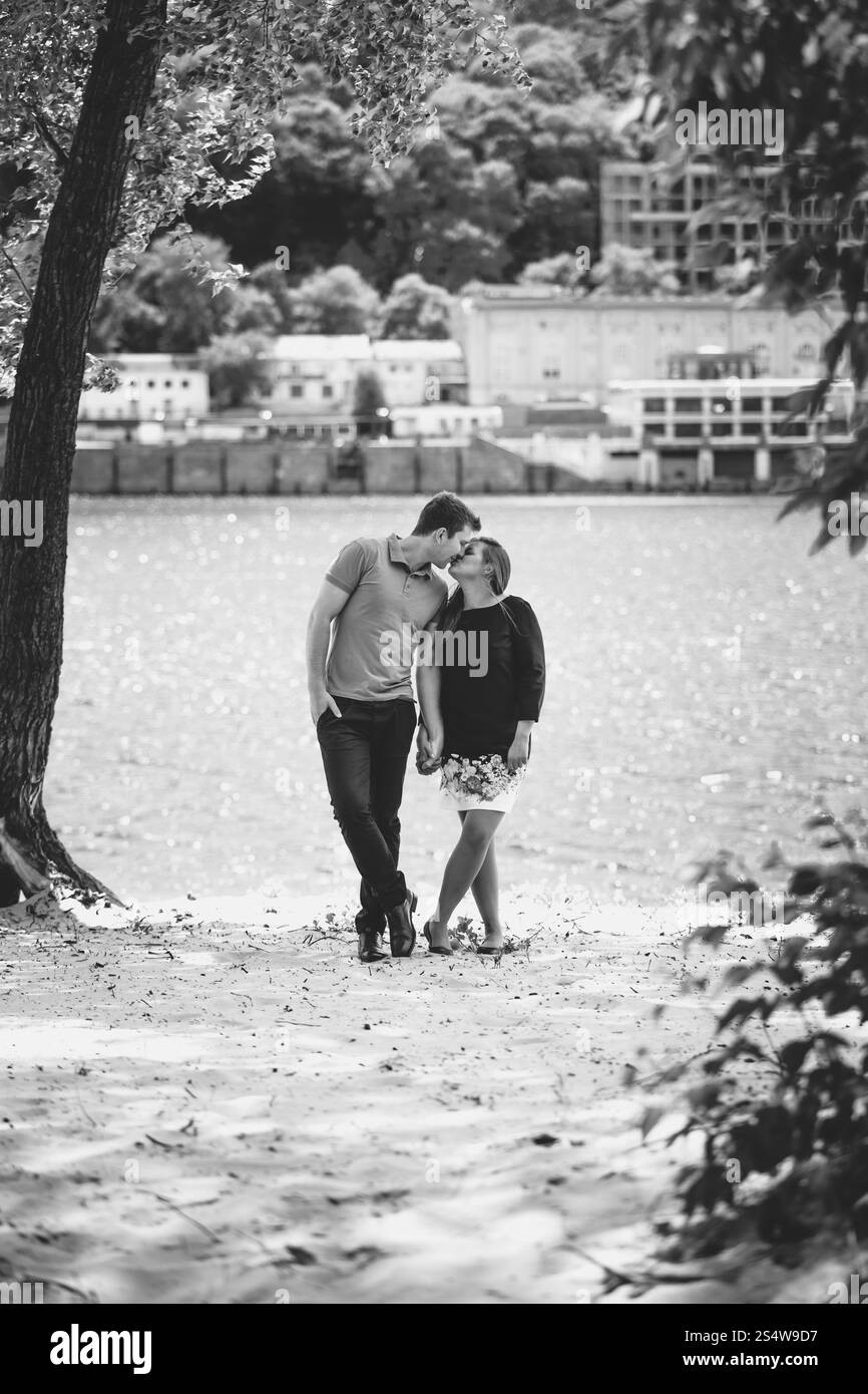 Photo en noir et blanc d'un jeune couple amoureux s'embrassant sur la rive Banque D'Images