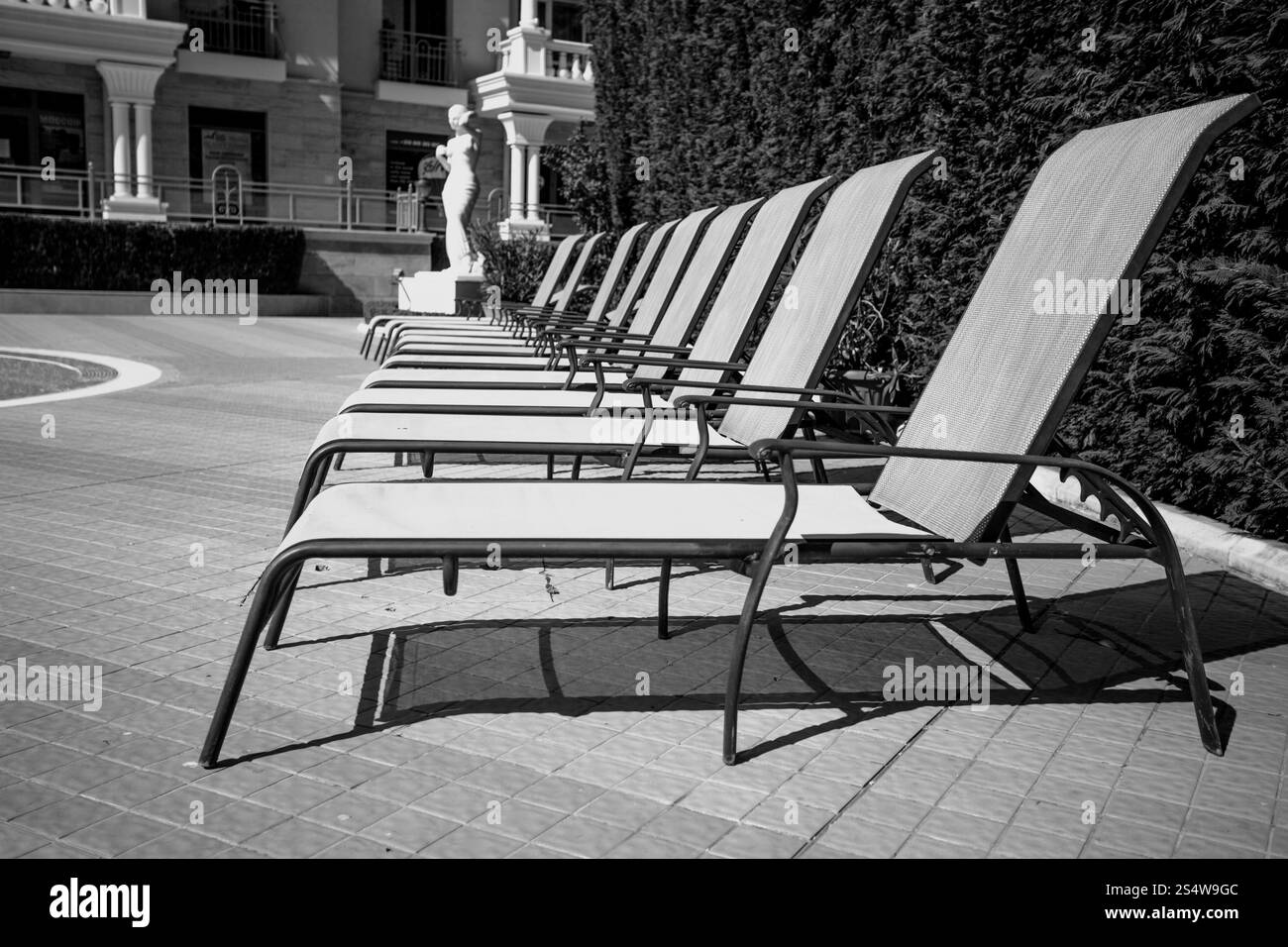 Tourné en noir et blanc de la rangée de chaises transats au bord de la piscine Banque D'Images