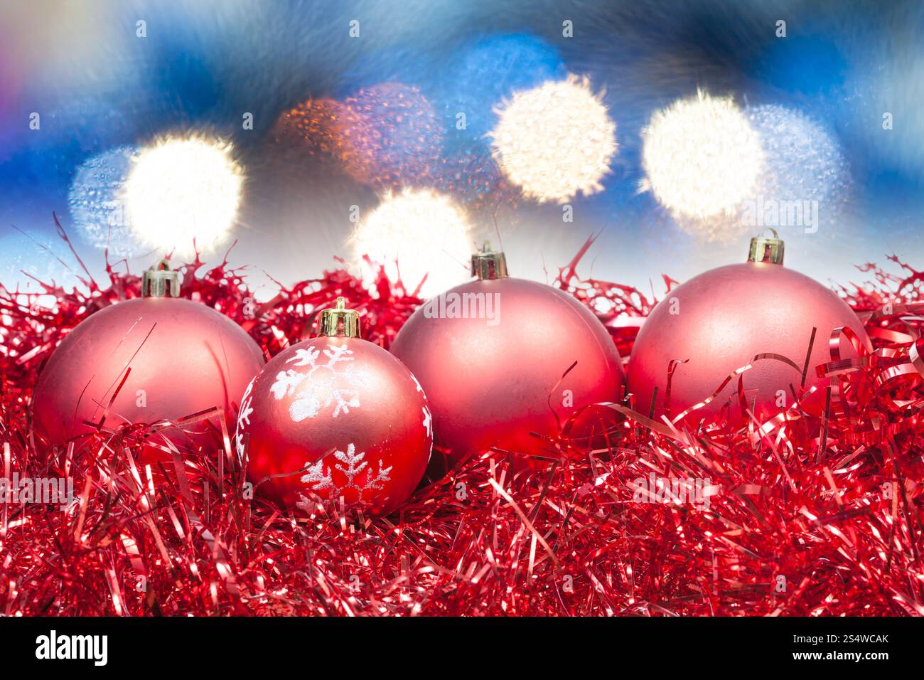 Xmas still life - boules rouges de Noël avec des lumières de Noël bleu background Banque D'Images