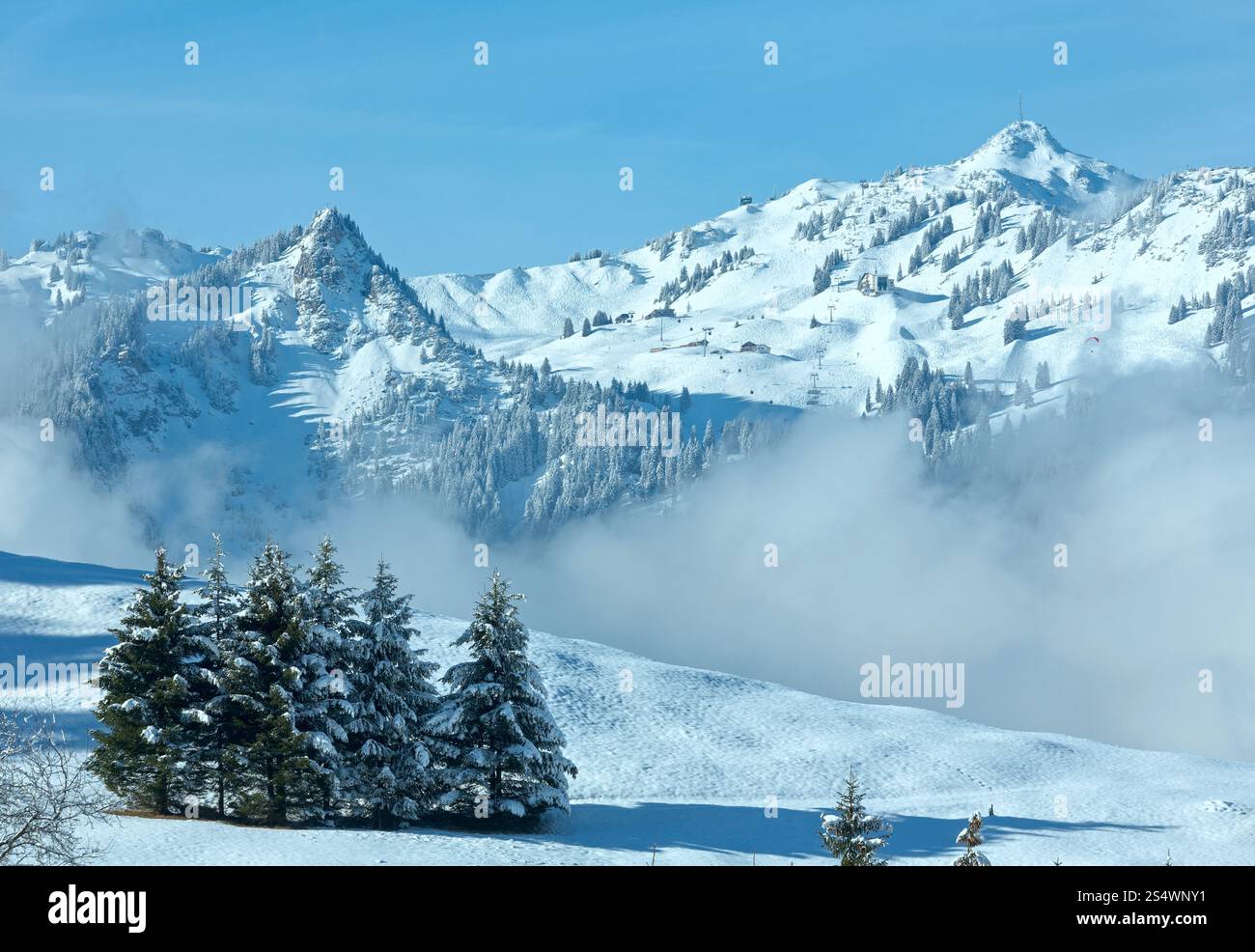 Paysage de montagne d'hiver avec les nuages bas de la pente (Autriche, Bavière). Banque D'Images
