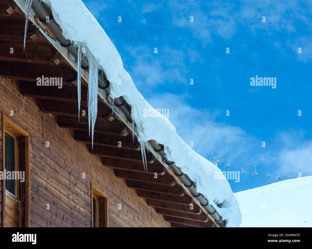 Maison en bois (avec la neige et de glaçons sur le toit) sur la pente de montagne d'hiver. Banque D'Images