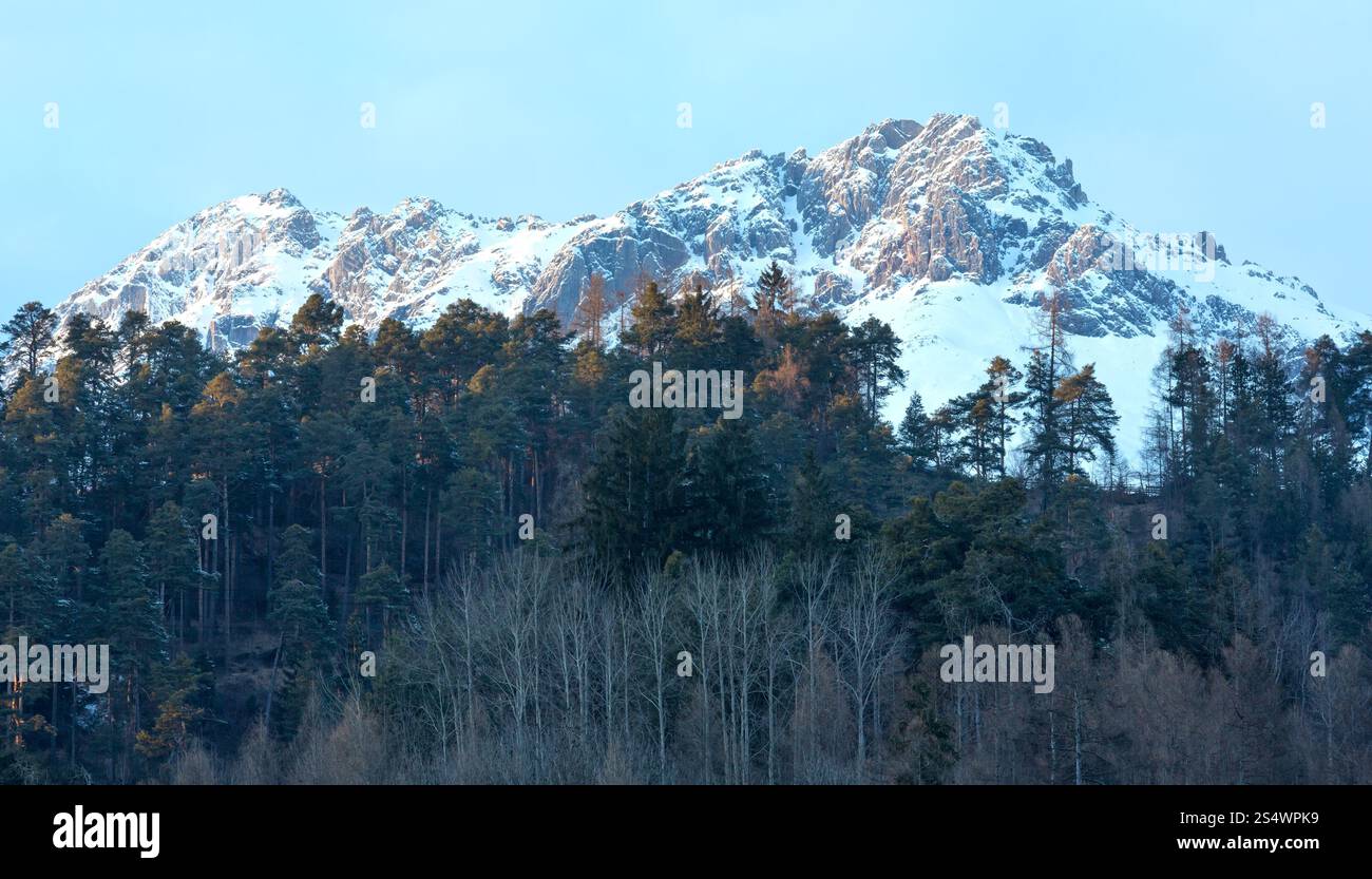 Paysage de soirée de montagne d'hiver avec forêt en face et mout dans la dernière lumière du soleil. Tyrol, Autriche. Banque D'Images