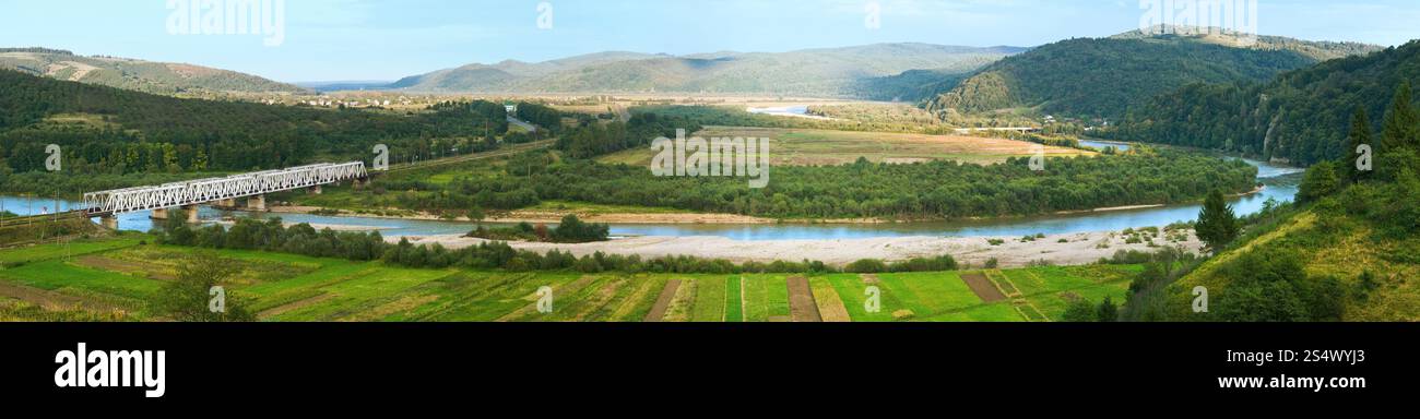 Panorama sur les contreforts de campagne du matin brumeux d'été avec chemin de fer et rivière (village de Werchnie Syniowydne, Skole Raion, oblast de Lviv, Ukraine). Banque D'Images