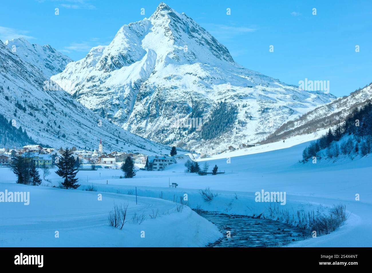 Vue sur les cours d'eau de montagne en hiver et village dans la vallée (Autriche). Banque D'Images