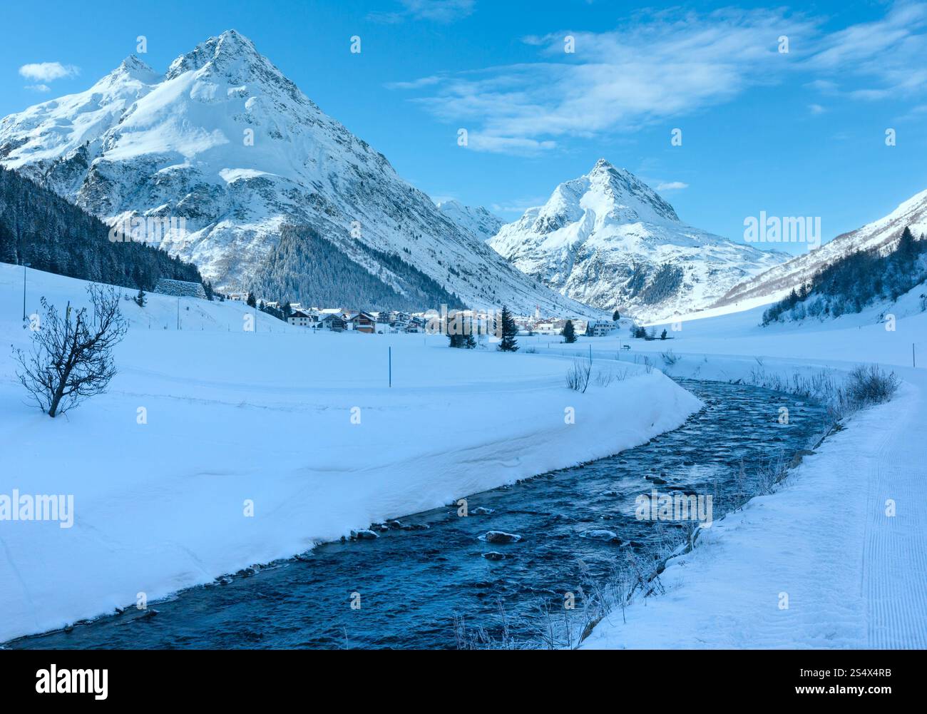 Vue sur les cours d'eau de montagne en hiver et village dans la vallée (Autriche). Banque D'Images