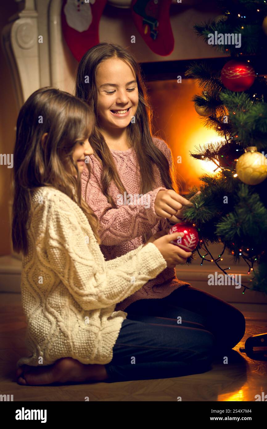 Photo aux couleurs de deux jolies filles assis sur le plancher et de la décoration de Noël Banque D'Images Photo aux couleurs de deux jolies filles assis sur le plancher et de la décoration de Noël Banque D'Images