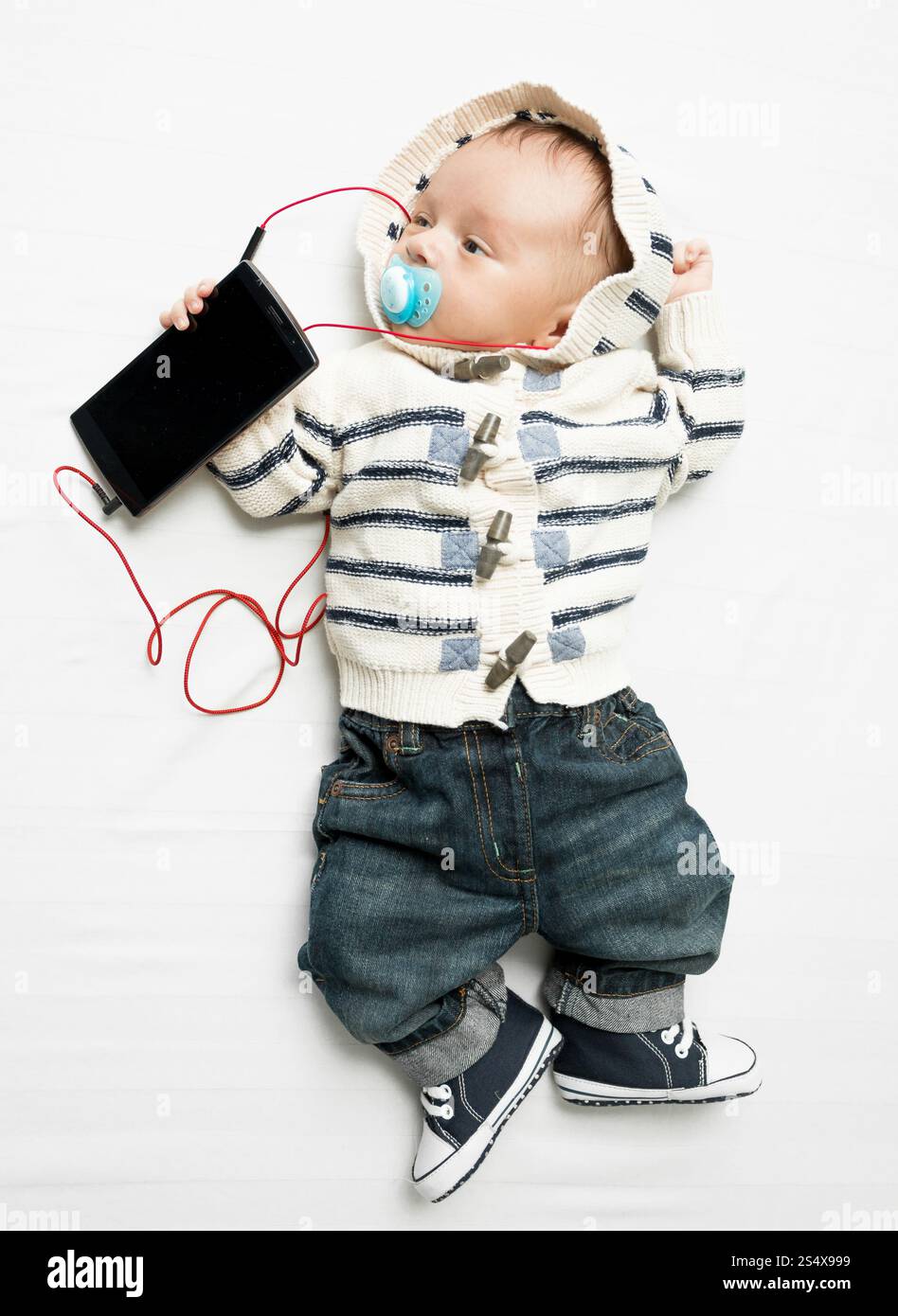 Funny photo de cute baby boy écouter de la musique sur votre téléphone avec écouteurs Banque D'Images