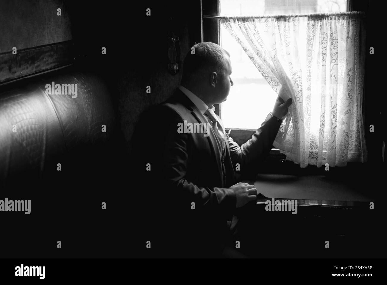Portrait monochrome de l'élégant homme assis en train coupé et à la fenêtre de Banque D'Images
