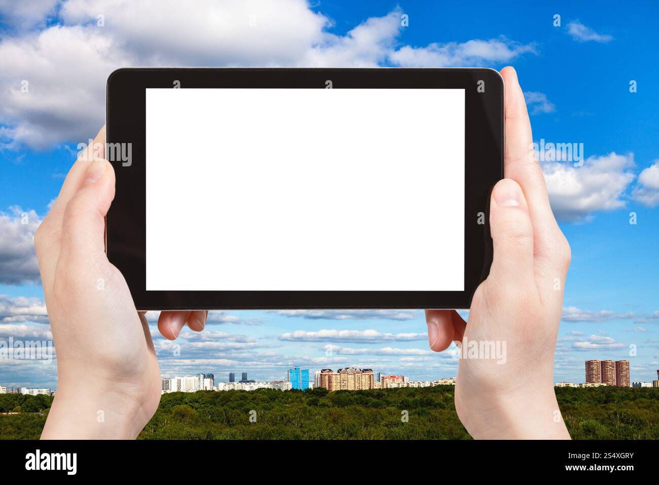 concept de saison - photographies touristiques ciel bleu avec des nuages blancs sur la ville et les arbres verts sur tablette pc avec écran découpé avec place vide pour Banque D'Images