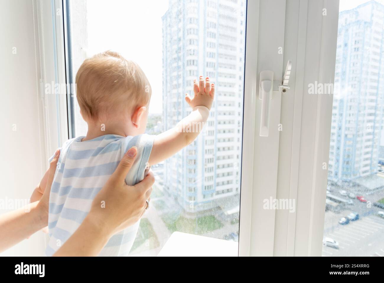 Photo gros plan de mother holding baby boy alors qu'il est à l'extérieur à travers la vitre Banque D'Images
