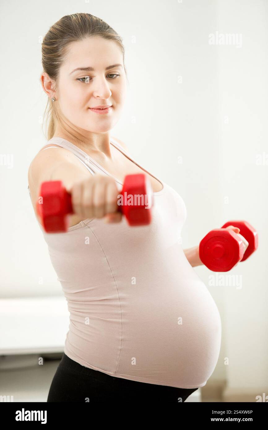Closeup portrait of pregnant woman exercising with dumbbells Banque D'Images