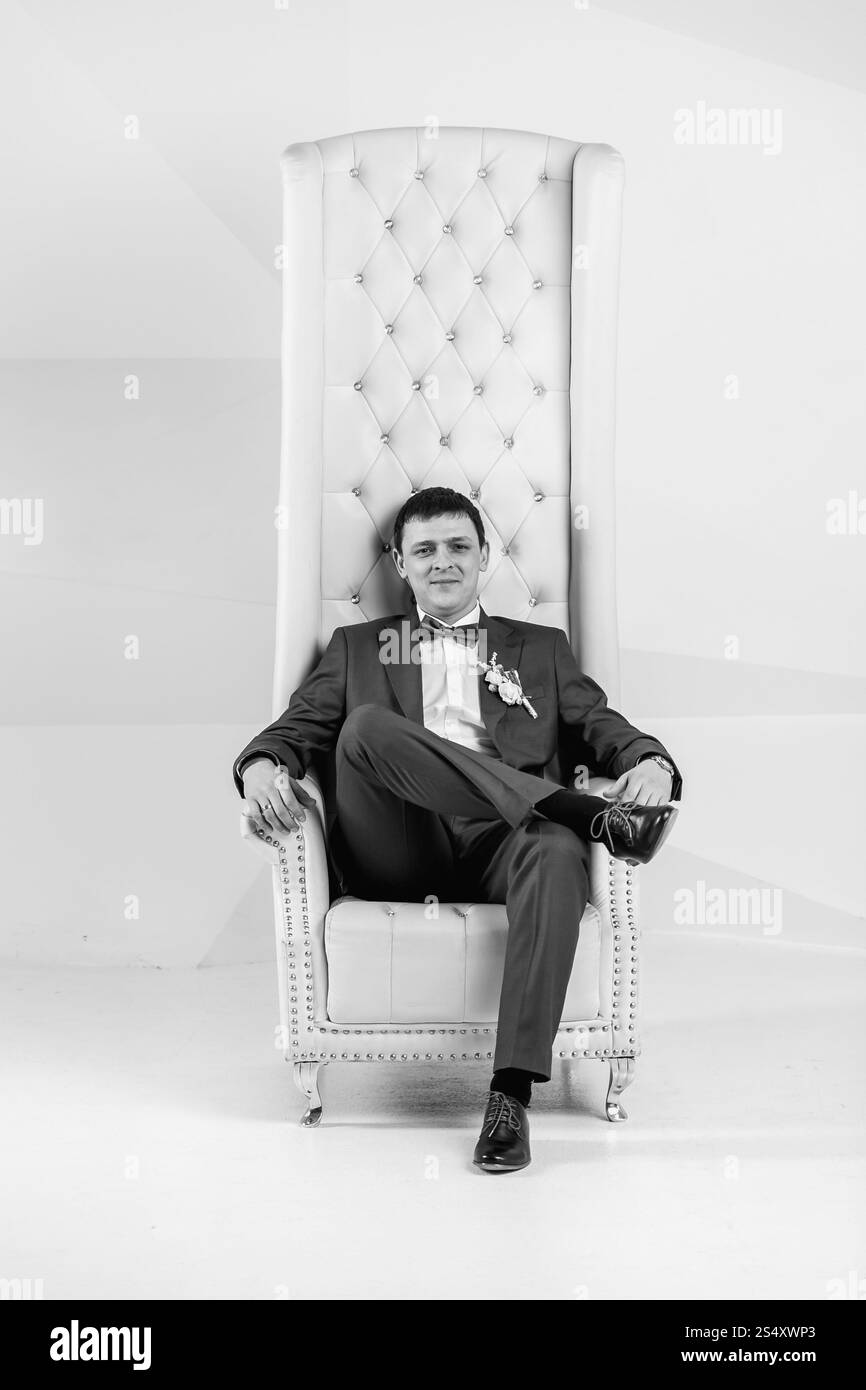 Le noir et blanc portrait of handsome man posing élégant au studio en fauteuil Banque D'Images