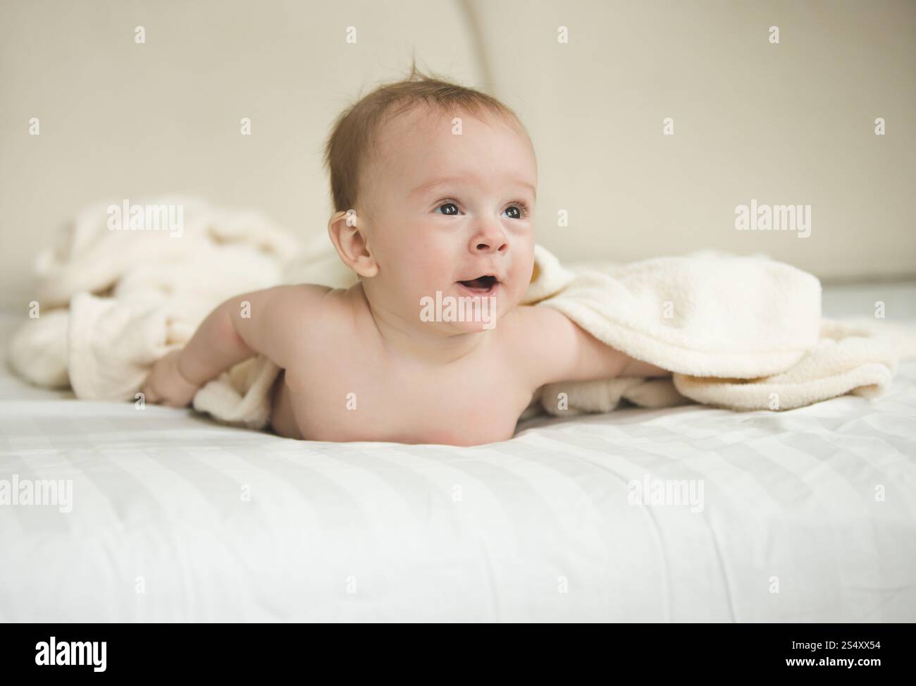 Portrait drôle de surprise baby boy lying under blanket on bed Banque D'Images