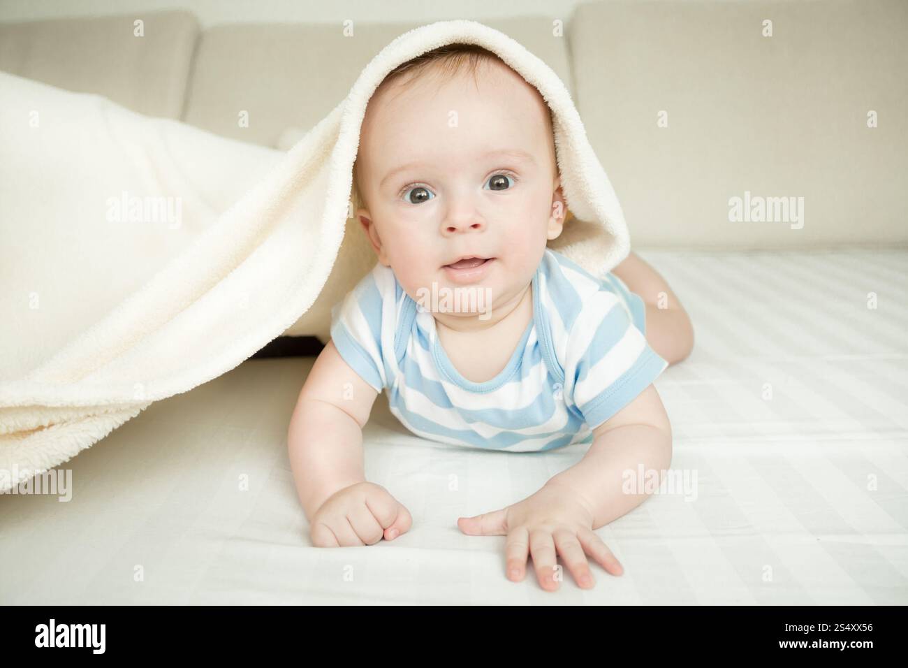 Tonique portrait of cute baby boy lying on bed sous la couverture Banque D'Images