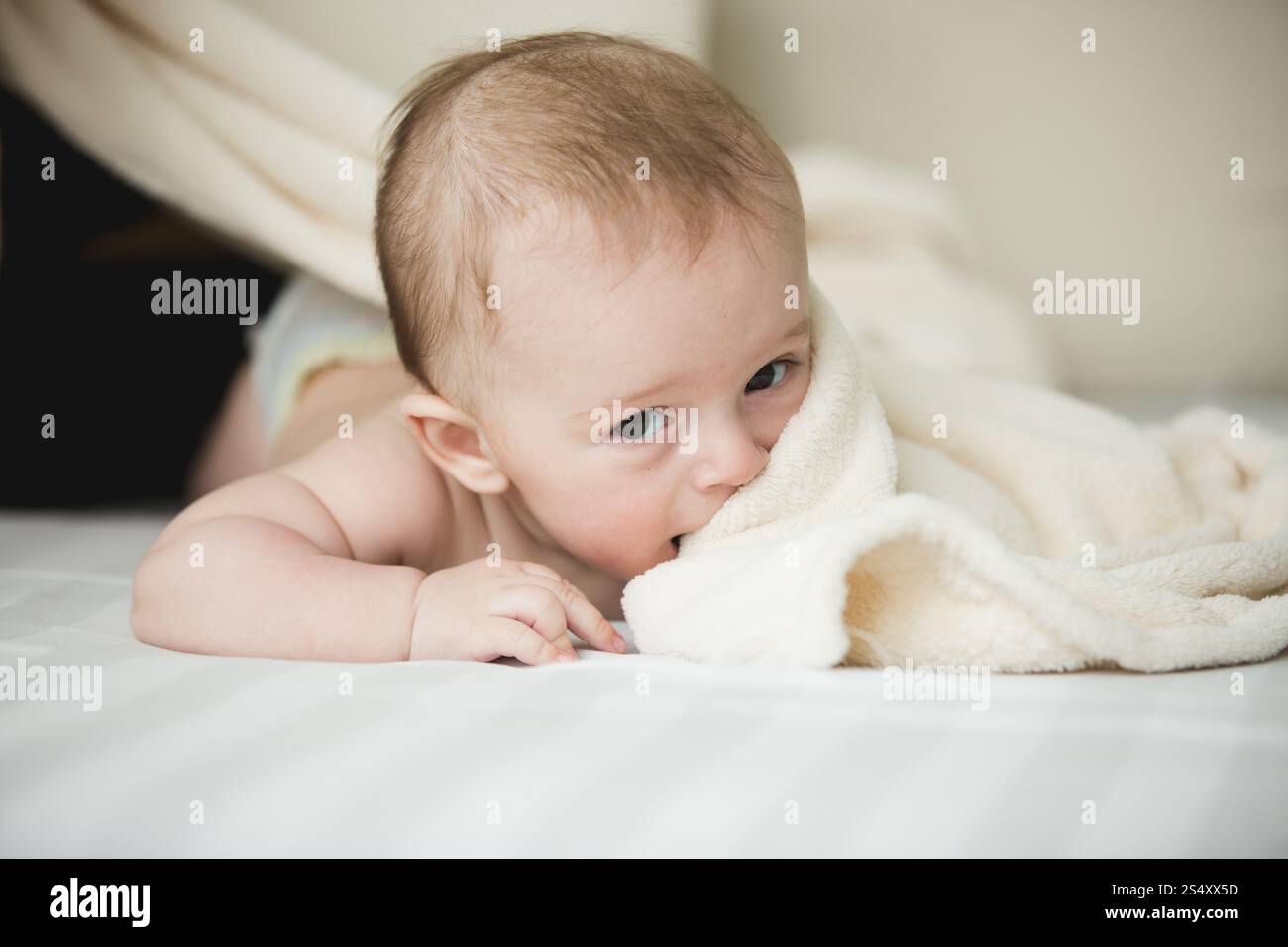 Portrait of cute 6 mois bébé couché sur des draps blancs Banque D'Images